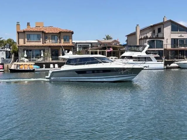 Slide: The Image of 2013 Jeanneau NC11 cruising on a calm waterfront near luxury homes. - 18