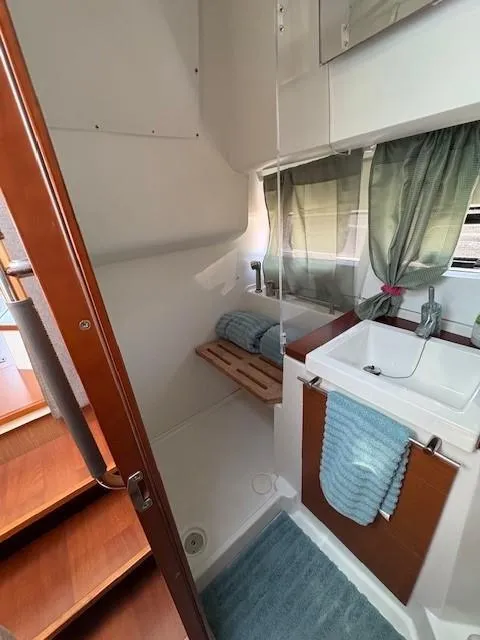 Slide: The Image of 2013 Jeanneau NC11 bathroom with sink, wooden accents, and window curtains. - 14
