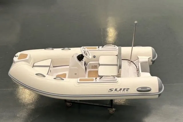 The Image of A sleek, white inflatable boat with gray accents and a central steering console. - 1