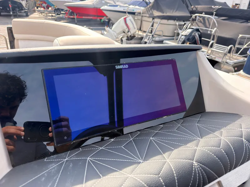 Slide: The Image of A Simrad screen on a 2027 Harris Grand Mariner 230, surrounded by cushioned seating. - 28
