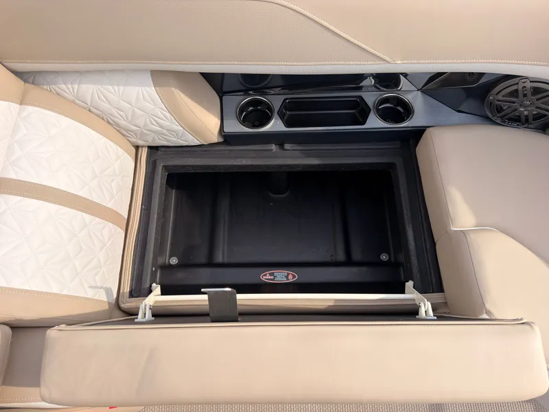 Slide: The Image of An open storage compartment in a boat with beige upholstery and cup holders. - 13