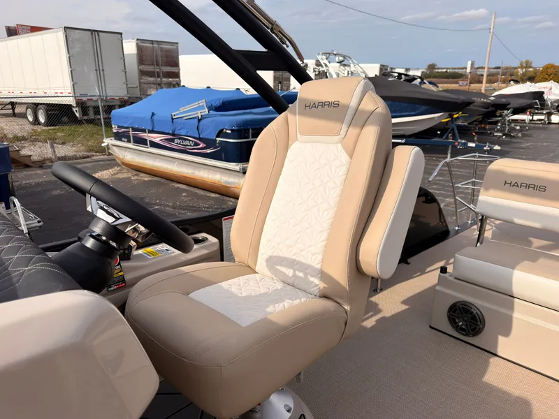 Slide: The Image of A 2027 Harris Grand Mariner 230 with a beige and white seat outdoors. - 27