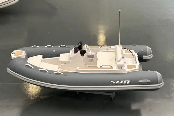 The Image of A gray inflatable boat with white seating and a console, displayed on a shiny floor. - 1