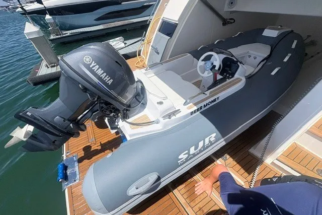 The Image of A gray inflatable boat with a Yamaha motor is docked. It features white seating and a steering wheel. - 0