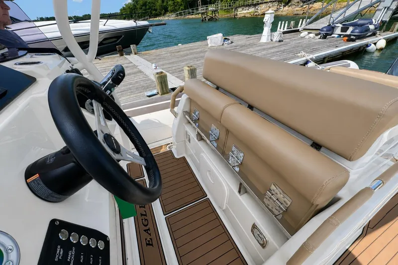 Slide: The Image of 2021 Brig Eagle 10 boat interior with steering wheel and tan seating at a dock. - 16