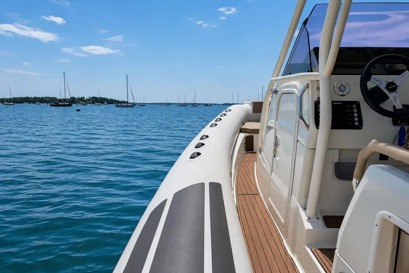 Slide: The Image of 2021 Brig Eagle 10 boat on calm blue water, clear sky, and distant sailboats. - 22