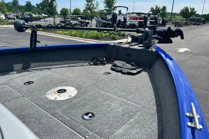 Slide: The Image of 2018 Tracker Pro Guide V-16 WT boat interior with fishing equipment in a parking lot. - 2
