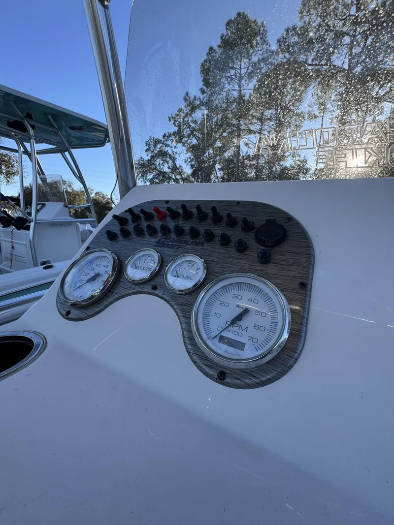 Slide: The Image of The image shows the dashboard of a Carolina Skiff 23 LS with multiple gauges and switches. - 12