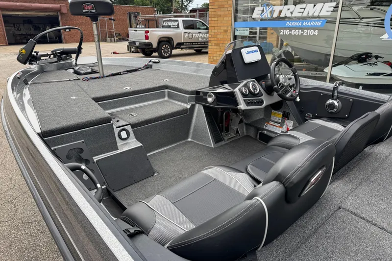 Slide: The Image of 2020 Ranger Z175 boat interior with steering console and seating, parked outside a marine shop. - 9