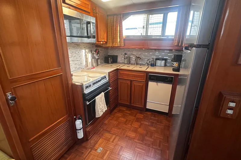 Slide: The Image of 1989 Jefferson Marquessa 52 yacht kitchen with wood cabinetry, modern appliances, and parquet flooring. - 18