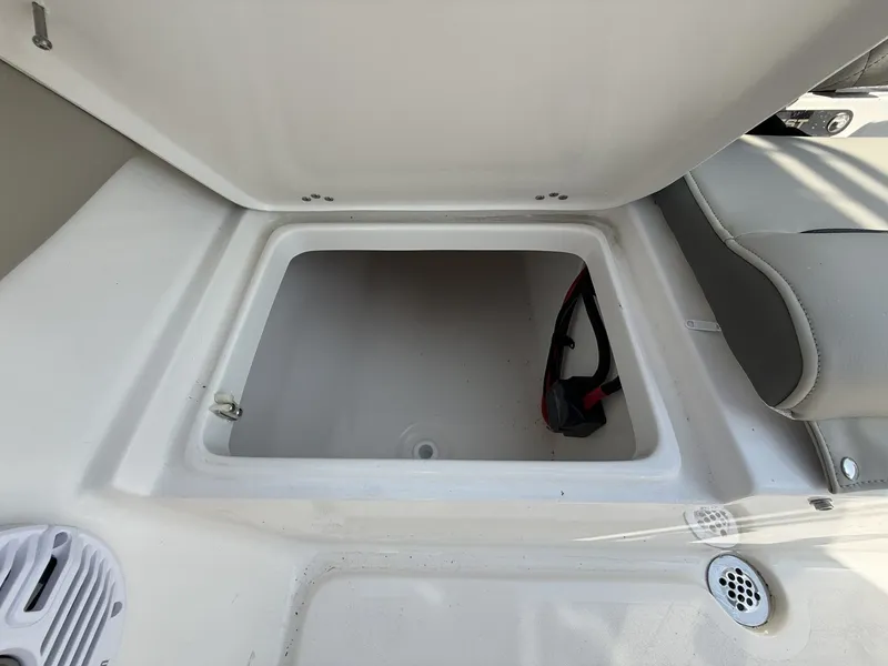 Slide: The Image of An open storage compartment on a boat with a gray seat beside it. - 14