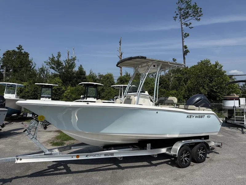 The Image of A 2027 Key West 203 FS boat on a trailer, surrounded by trees and other boats. - 1