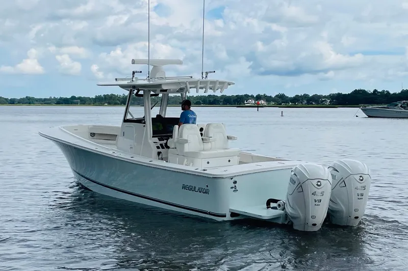 Slide: The Image of 2023 Regulator 31 boat on calm water with twin outboard engines. - 2