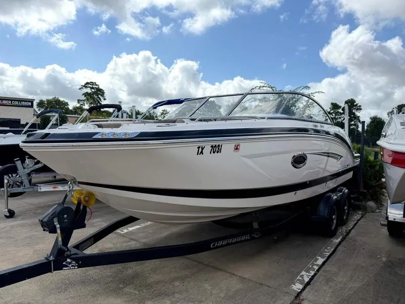 The Image of A white 2019 Chaparral boat sits on a trailer under a cloudy sky. - 1