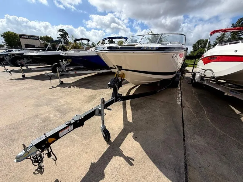Slide: The Image of A 2019 Chaparral boat on a trailer, surrounded by other boats in a parking area. - 23