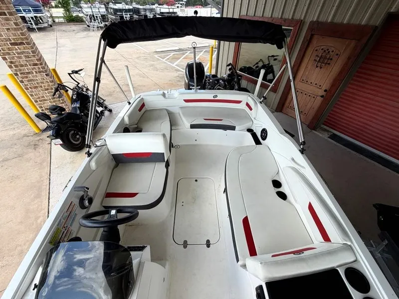 Slide: The Image of A white 2020 Godfrey boat with red accents, parked in a warehouse setting. - 18