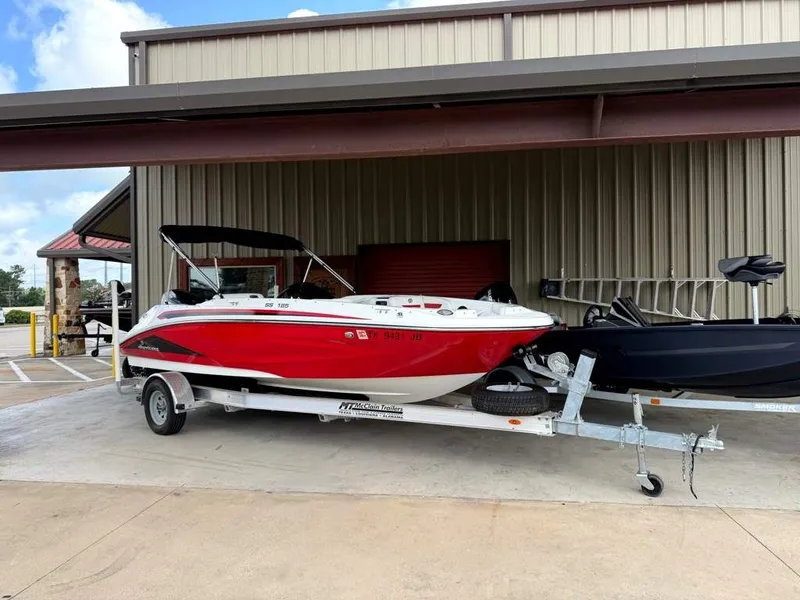 The Image of A red 2020 Godfrey boat is on a trailer in front of a building. - 1