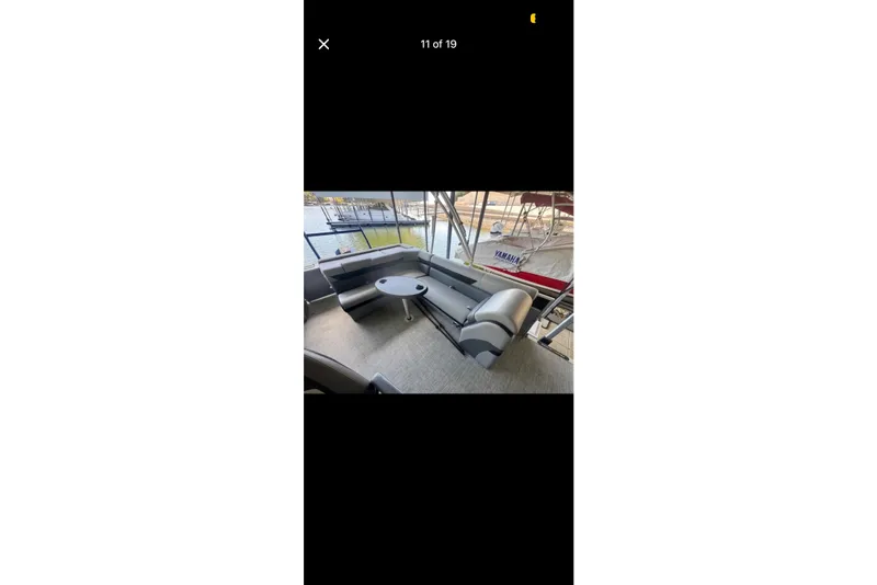 Slide: The Image of 2022 South Bay 25 CTS pontoon boat interior with seating and table, docked by the water. - 11