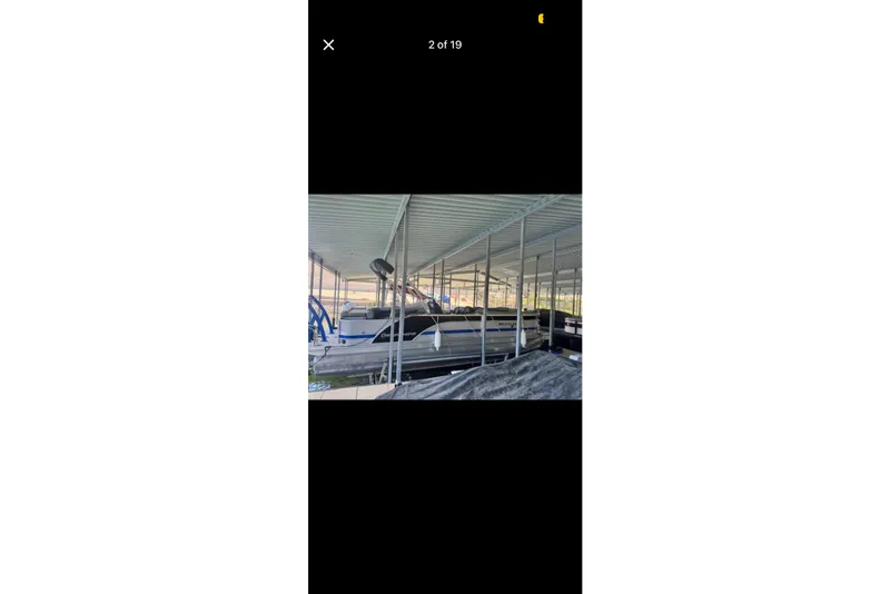 Slide: The Image of 2022 South Bay 25 CTS pontoon boat docked under a covered marina. - 2
