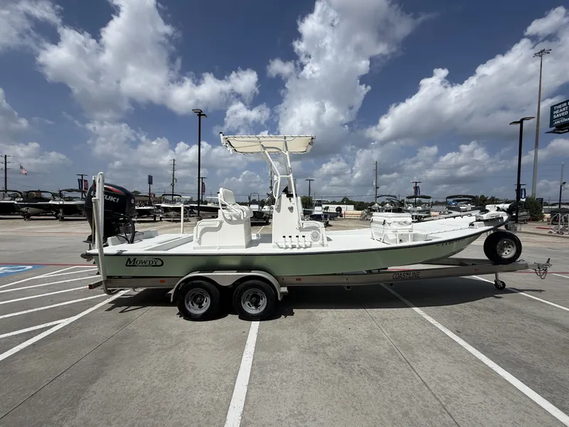 Slide: The Image of A 2015 Mowdy C-25 boat on a trailer, parked in a lot under a cloudy sky. - 7
