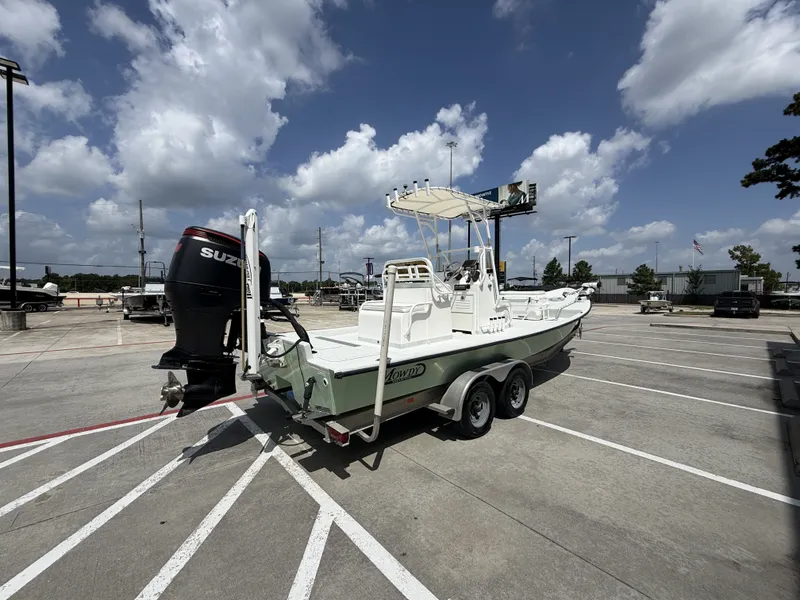 Slide: The Image of A 2015 Mowdy C-25 boat on a trailer in a parking lot under a blue sky. - 8