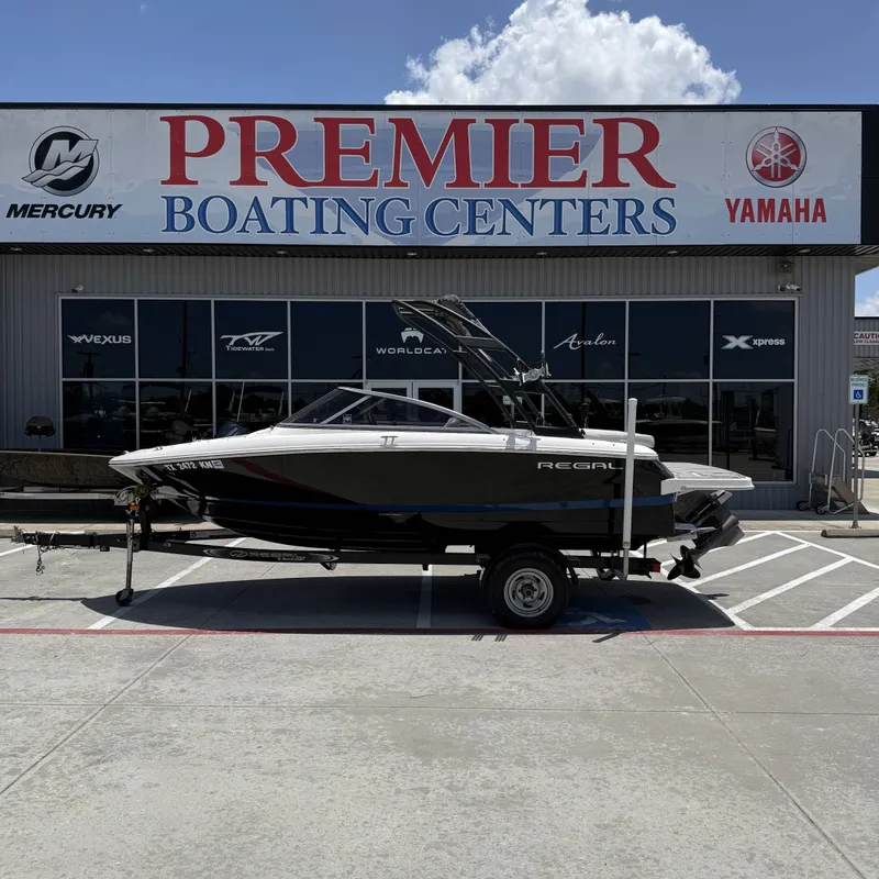 The Image of A 2019 Regal 1900ES SURF boat on a trailer in front of a boating center. - 1