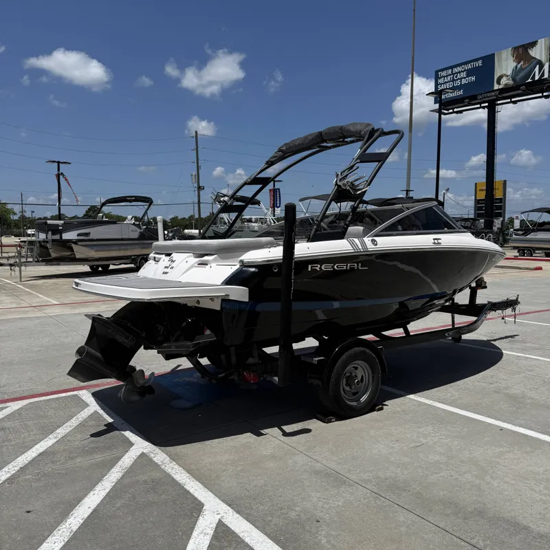 Slide: The Image of A black 2019 Regal 1900ES SURF boat on a trailer in a parking lot. - 8
