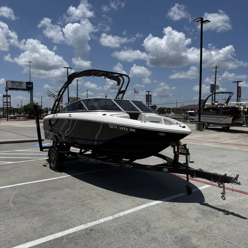 Slide: The Image of A 2019 Regal 1900ES SURF boat on a trailer in a parking lot under a cloudy sky. - 6