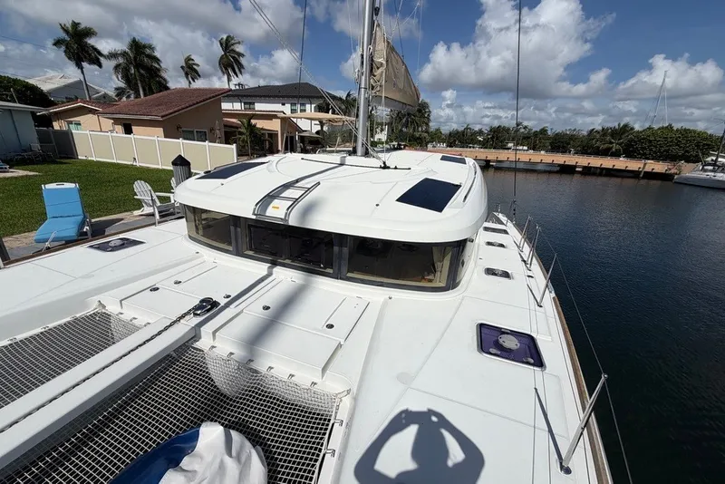 Slide: The Image of 2020 Lagoon 40 catamaran docked by waterfront homes under a clear blue sky. - 2