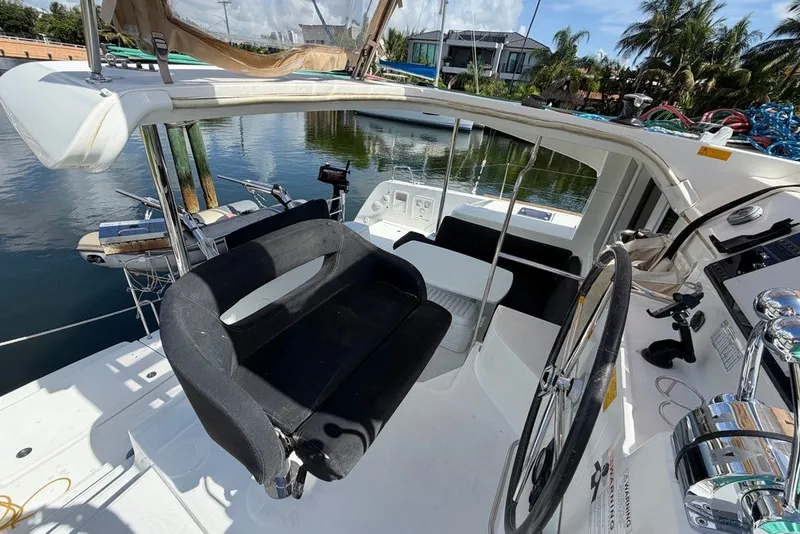 Slide: The Image of 2020 Lagoon 40 catamaran cockpit with steering wheel and seating, docked by the water. - 31