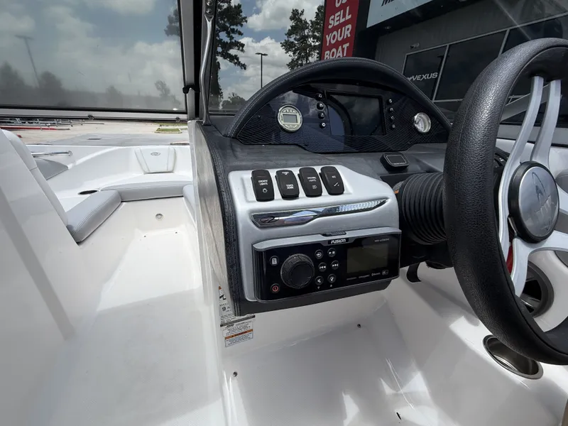 Slide: The Image of The image shows the cockpit of a 2019 Regal 1900ES SURF boat. There's a steering wheel, control buttons, and a radio. - 16