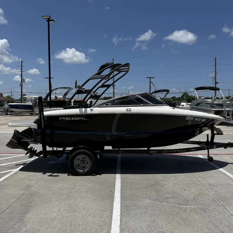 Slide: The Image of A black 2019 Regal 1900ES SURF boat on a trailer in a parking lot. - 7