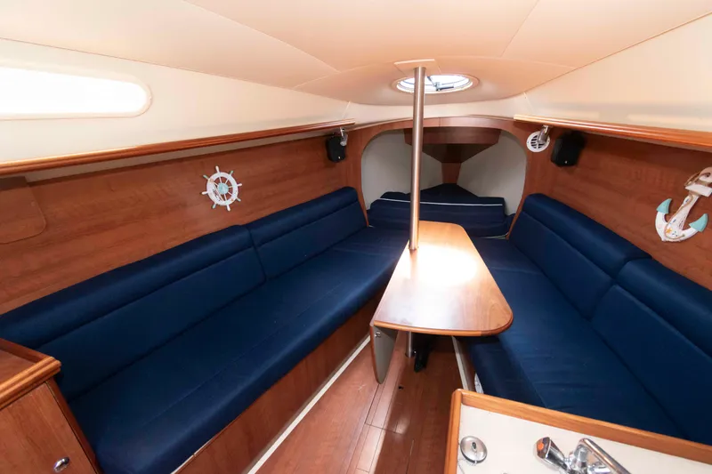 Slide: The Image of Interior of 2013 Marlow-Hunter 27 sailboat with blue seating and wooden accents. - 16