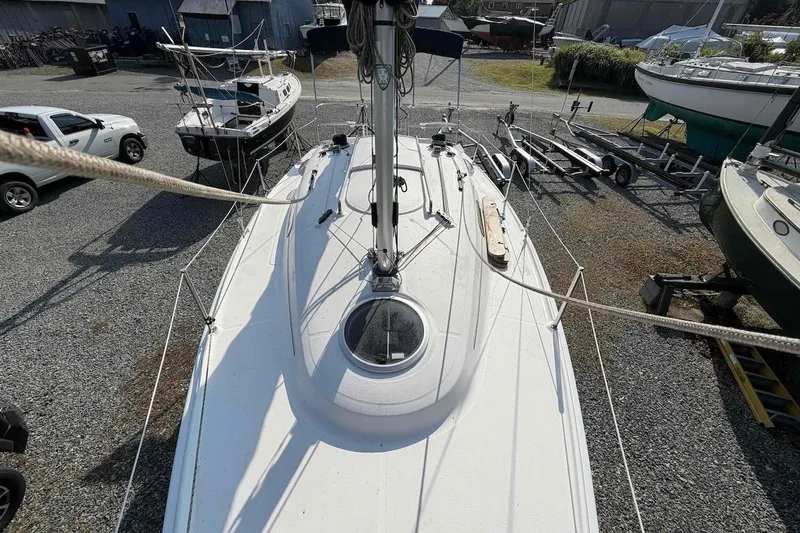 Slide: The Image of 2013 Marlow-Hunter 27 sailboat on gravel lot with trailers and vehicles nearby. - 8