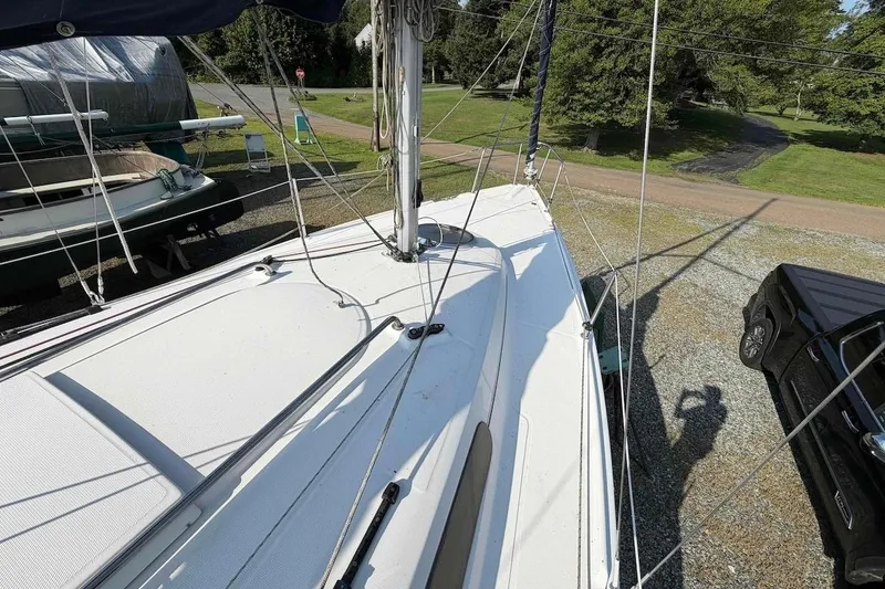 Slide: The Image of 2013 Marlow-Hunter 27 sailboat deck with rigging, parked on gravel near trees. - 7