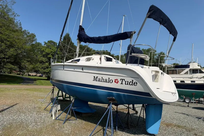 Slide: The Image of 2013 Marlow-Hunter 27 sailboat on stands, named "Mahalo Tude," in a boatyard setting. - 4