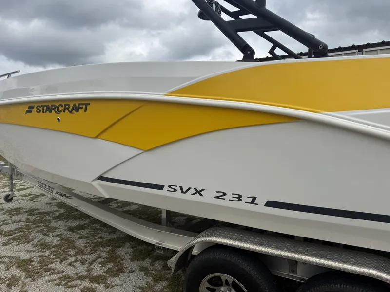 The Image of A 2025 Starcraft SVX 231 OB boat with yellow and white accents on a trailer. - 1