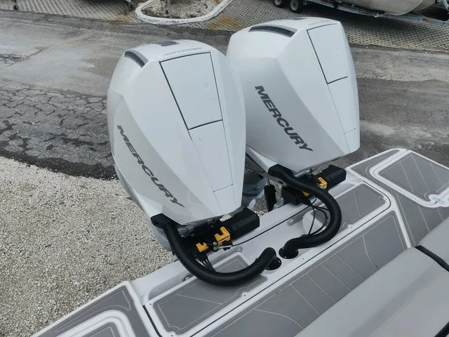 Slide: The Image of Two white Mercury outboard engines are mounted on a boat, situated on a paved area. - 6