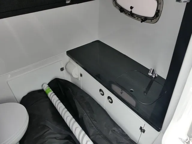 Slide: The Image of The image shows a modern boat bathroom with a sink, toilet, and storage space. - 19