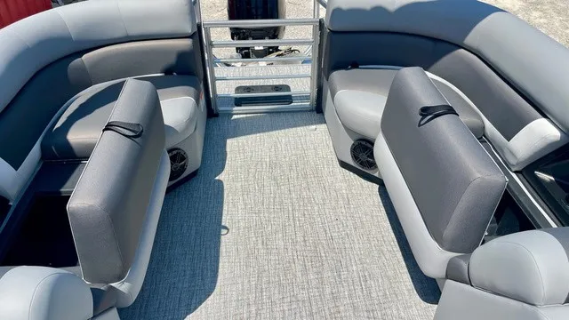 Slide: The Image of The image shows the interior of a Landau Island Breeze 23C Sport Rear Lounge Trit pontoon boat with gray upholstery and carpeted flooring. - 12