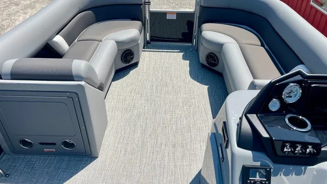 Slide: The Image of The image shows the interior of a Landau Island Breeze 23C Sport Rear Lounge Trit pontoon boat. It features gray upholstery and a modern dashboard. - 6