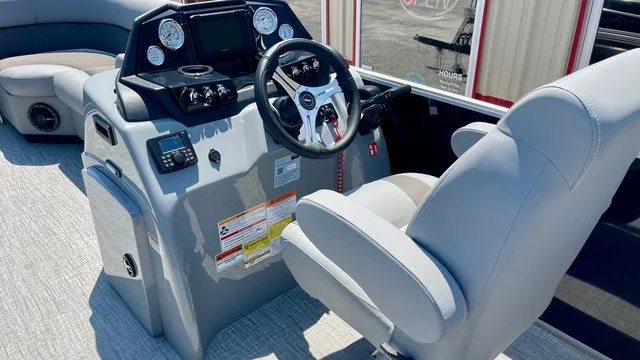 Slide: The Image of The image shows the cockpit of a Landau Island Breeze 23C Sport Rear Lounge Trit pontoon boat. It features a modern dashboard with multiple gauges and a steering wheel. - 16