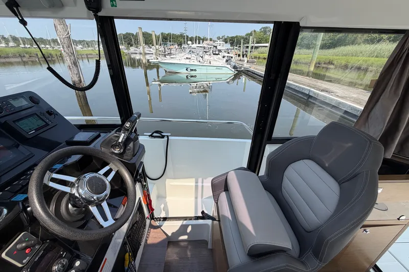 Slide: The Image of Interior of 2020 Jeanneau NC Sport 895 boat, featuring helm and seating, docked at marina. - 27