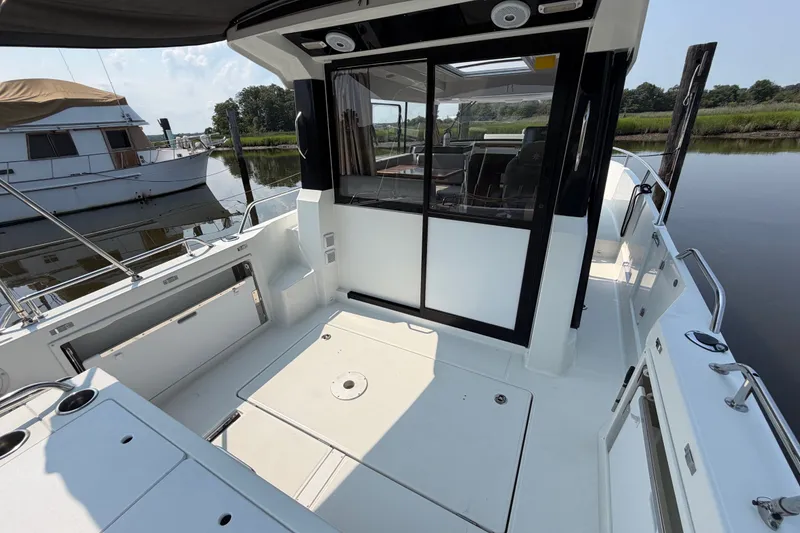 Slide: The Image of 2020 Jeanneau NC Sport 895 boat deck with sliding glass doors, docked by the water. - 48