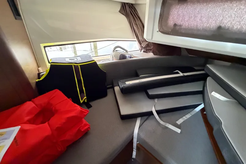 Slide: The Image of Interior of 2020 Jeanneau NC Sport 895 with life jackets and cushions on a cabin bed. - 32