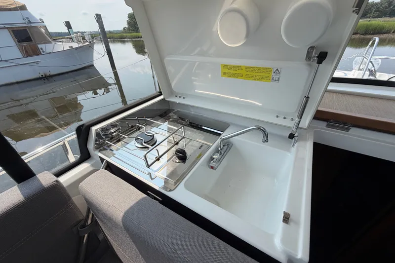 Slide: The Image of 2020 Jeanneau NC Sport 895 boat kitchen with stove and sink by the water. - 28