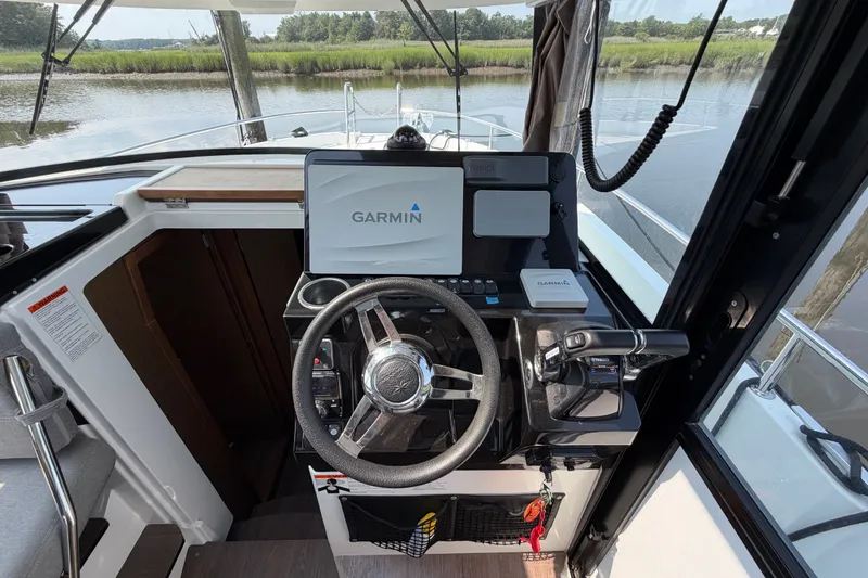 Slide: The Image of Cockpit of 2020 Jeanneau NC Sport 895 with Garmin navigation system, steering wheel, and throttle controls. - 22