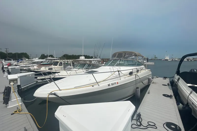 Slide: The Image of 2000 Sea Ray 270 Sundancer docked at marina, surrounded by other boats under cloudy sky. - 2