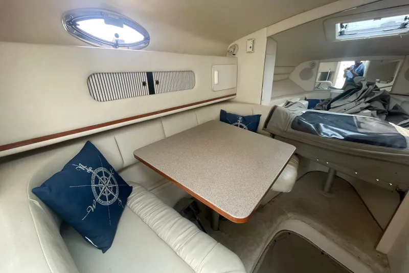 Slide: The Image of Interior of 2000 Sea Ray 270 Sundancer boat with cozy seating and nautical-themed pillows. - 9