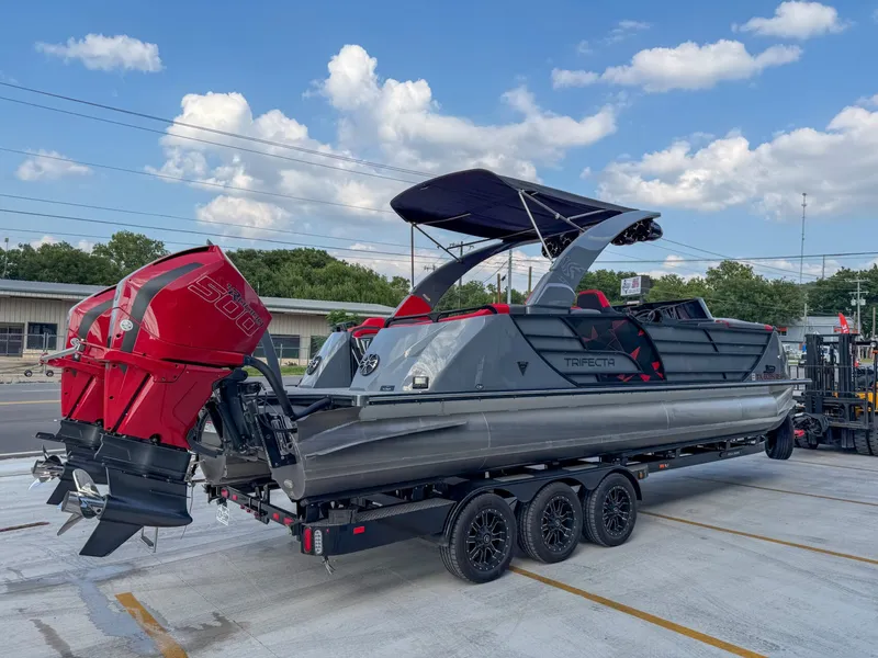 Slide: The Image of A modern pontoon boat with a red outboard motor and black bimini top sits on a trailer. - 6